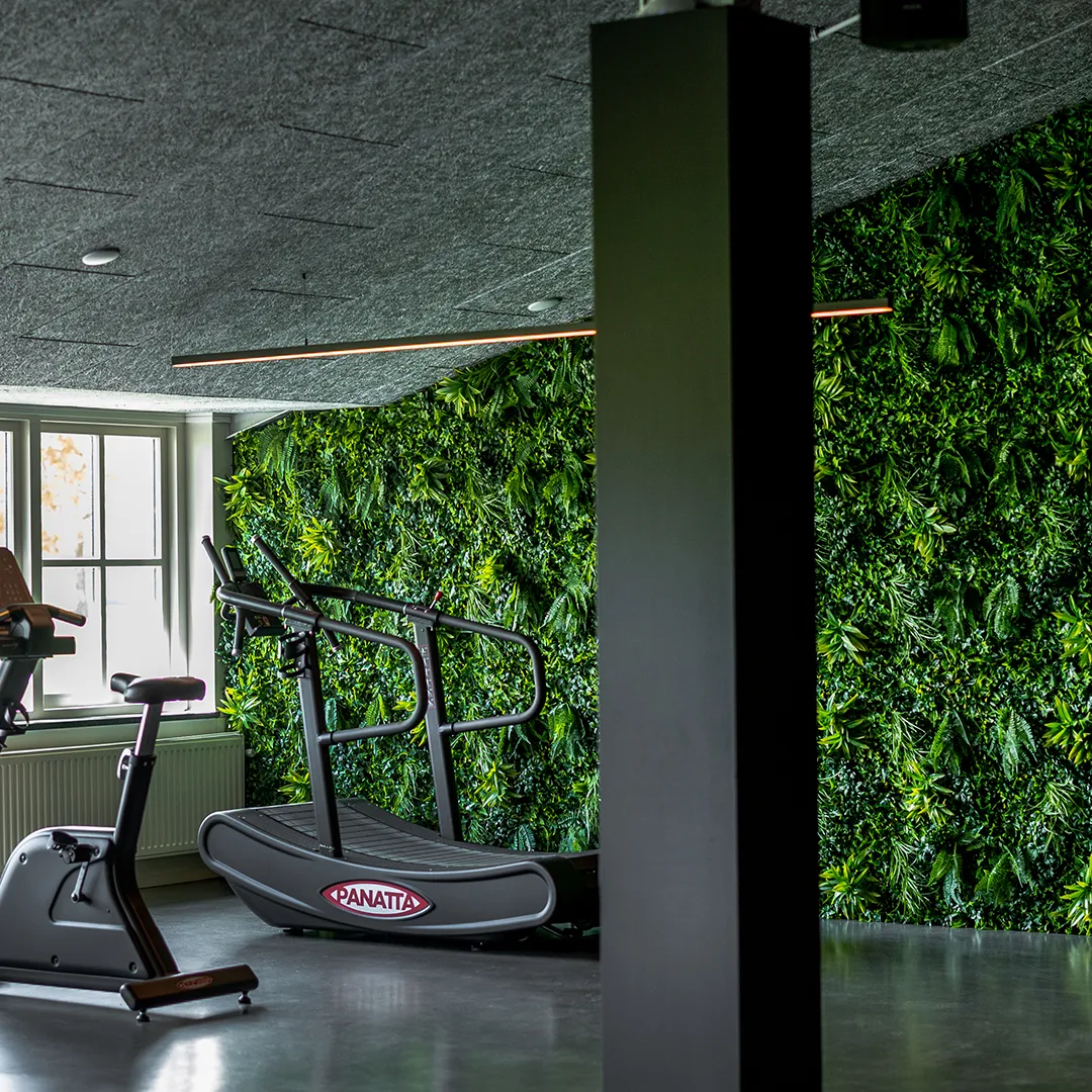 Moderne fitnessruimte met verticale plantenwand en professionele sportapparatuur voor zakelijk welzijn