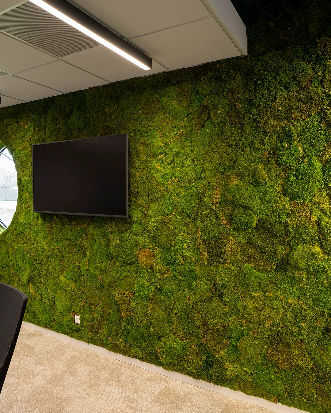 Grote mosswand met ingebouwde flatscreen tv in een moderne vergaderruimte — groene wanddecoratie voor kantoor door Miverde