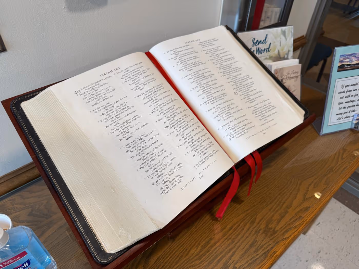 Open Bible on a wooden stand displaying the book of Isaiah with red ribbons as bookmarks.
