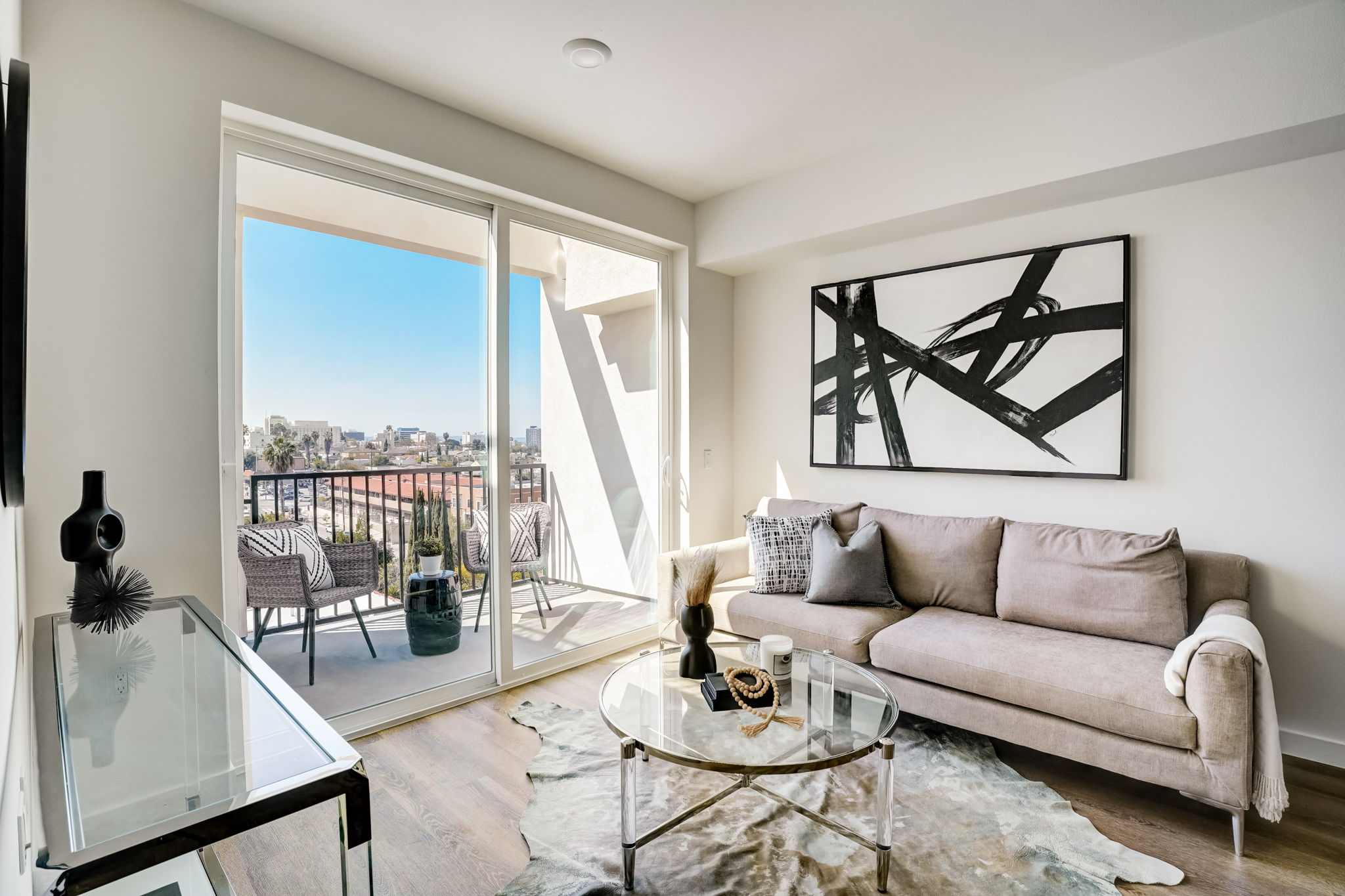 Furnished staged living area with sofa, coffee table, and view onto balcony