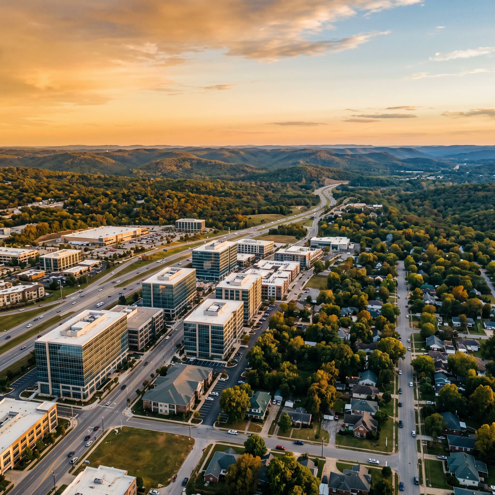 Aerial view of Northwest Arkansas spanning commercial towers to residential rooftops toward the Ozarks