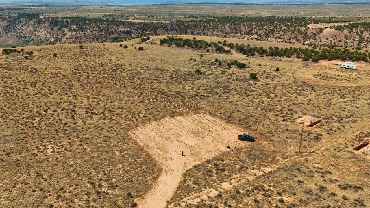 Aerial view of open land in Duchesne County, Utah, featuring sparse vegetation, a dirt road, and a person standing near a vehicle, showcasing potential land for sale by Mountains West Ranches.