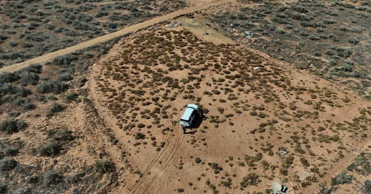Solitary vehicle in a sparse Utah desert landscape, highlighting land clearing considerations for potential buyers.