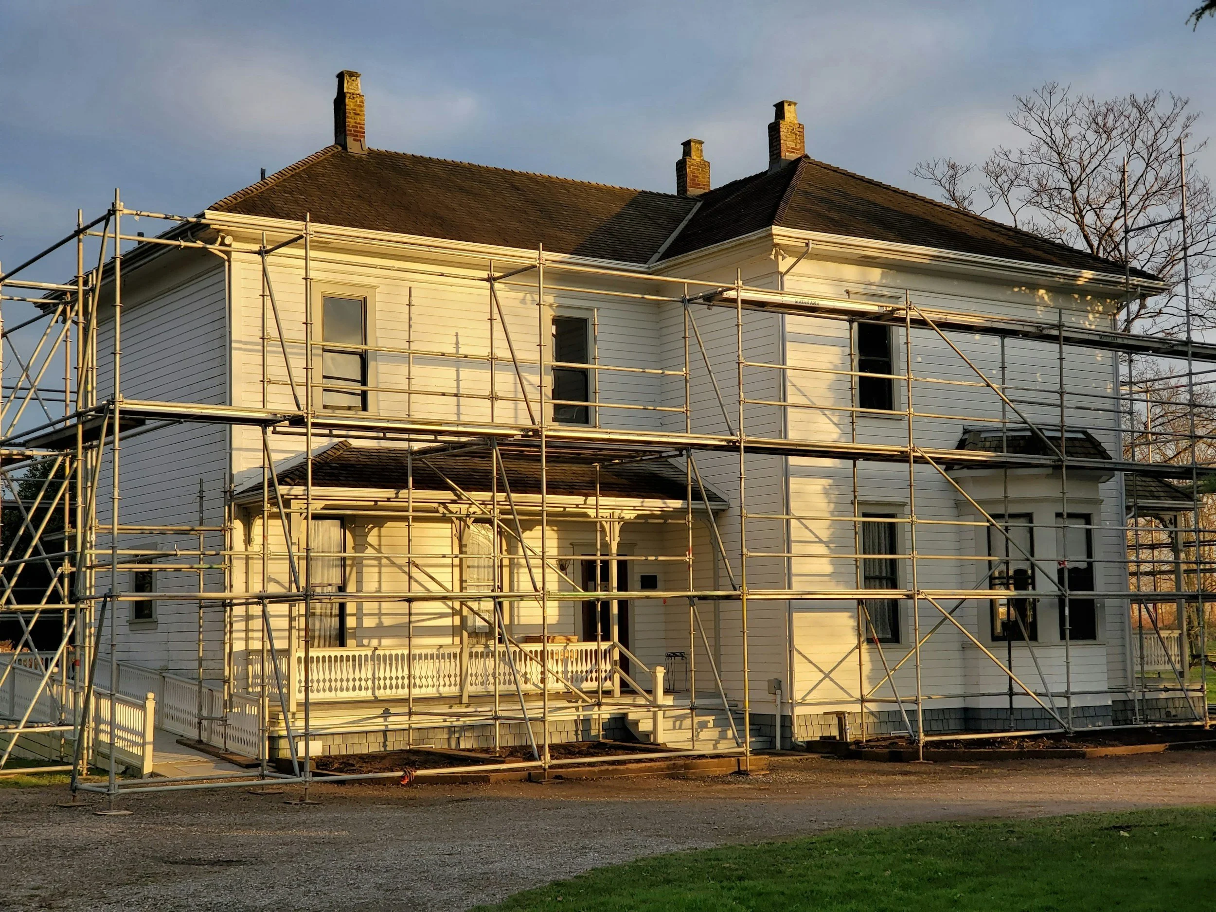 House under renovation with scaffolding, showcasing improvements for rural property development and budgeting.