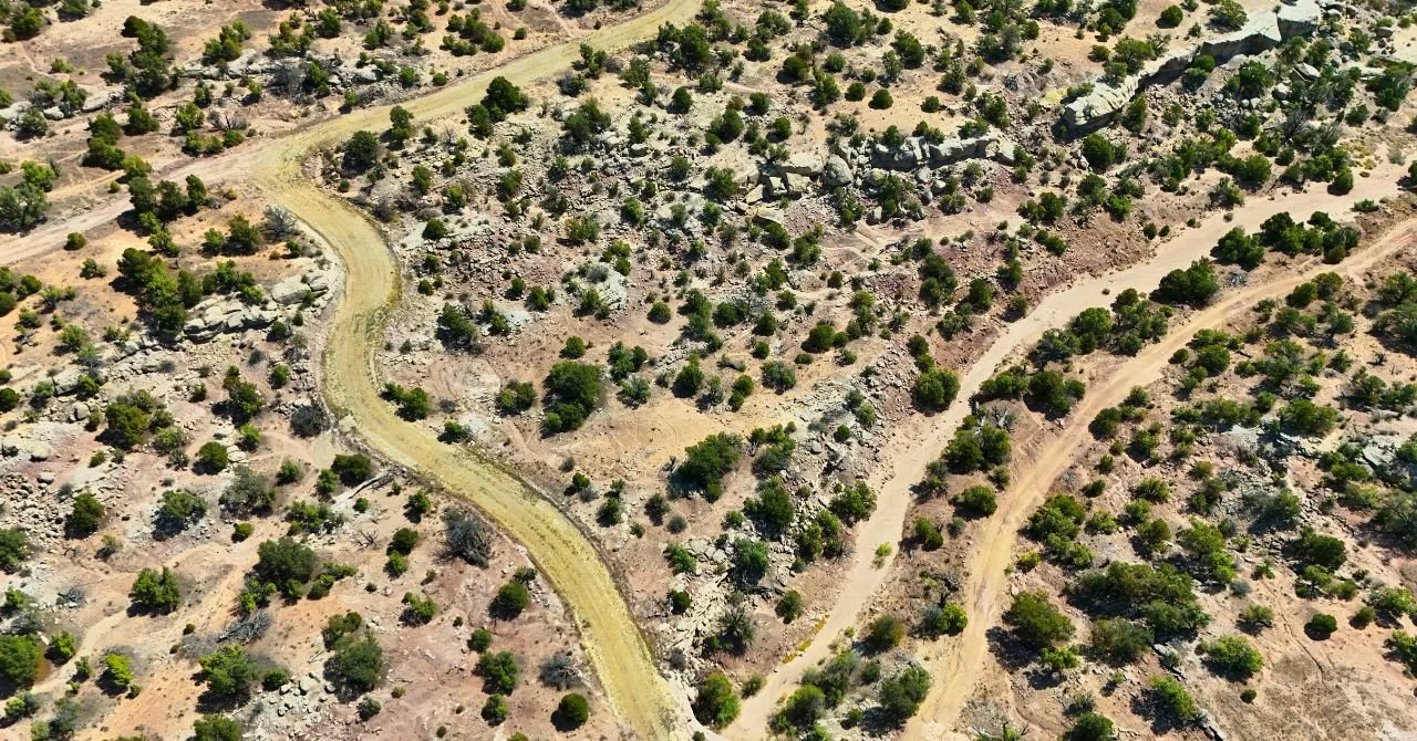 Aerial view of rural Utah land featuring winding dirt roads, scattered shrubs, and rocky terrain, highlighting potential for land investment and development.