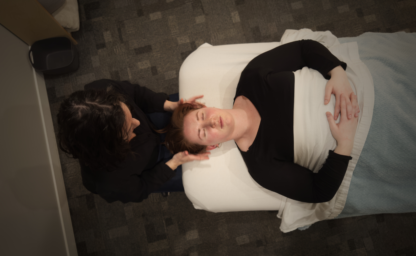 Overhead view of a woman receiving a head massage while lying on a massage table with a white blanket.