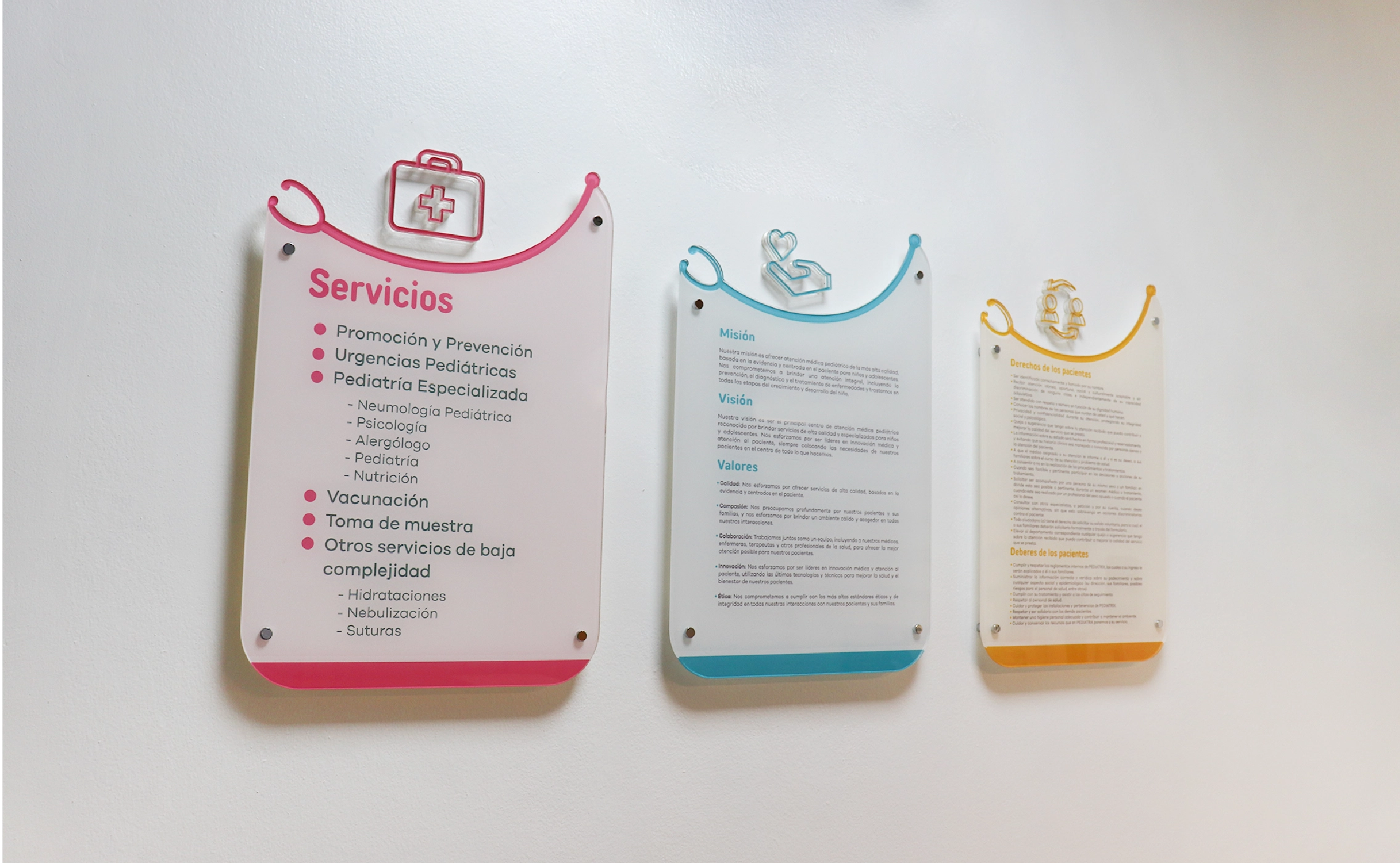 Three wall-mounted informational panels displaying pediatric medical services, mission and values, and patient rights and duties, each with colored header icons.