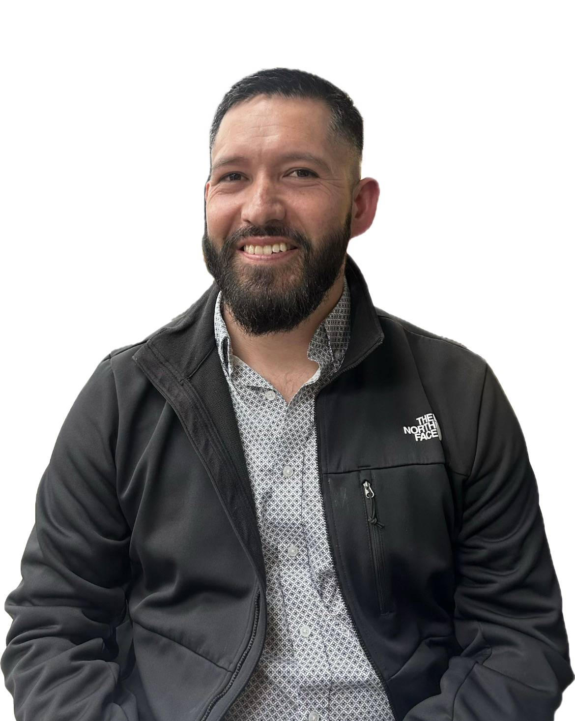 Smiling Antonio Luna with a beard wearing a patterned shirt and a black The North Face jacket.