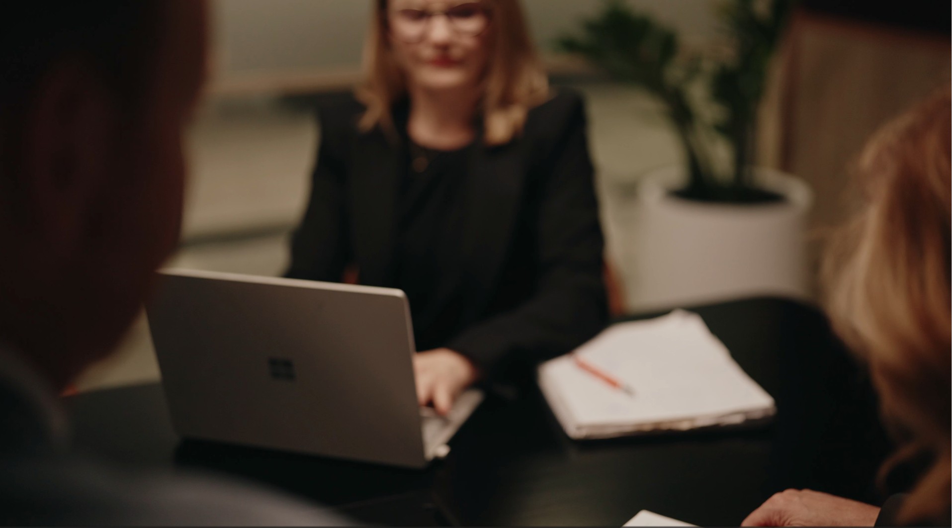 HR practitioner typing on a laptop across the desk from two clients