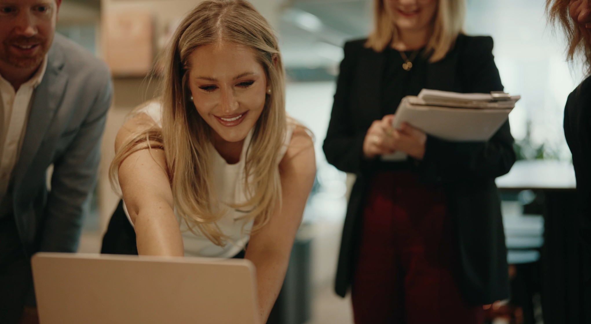Smiling team gathered around a laptop in an office