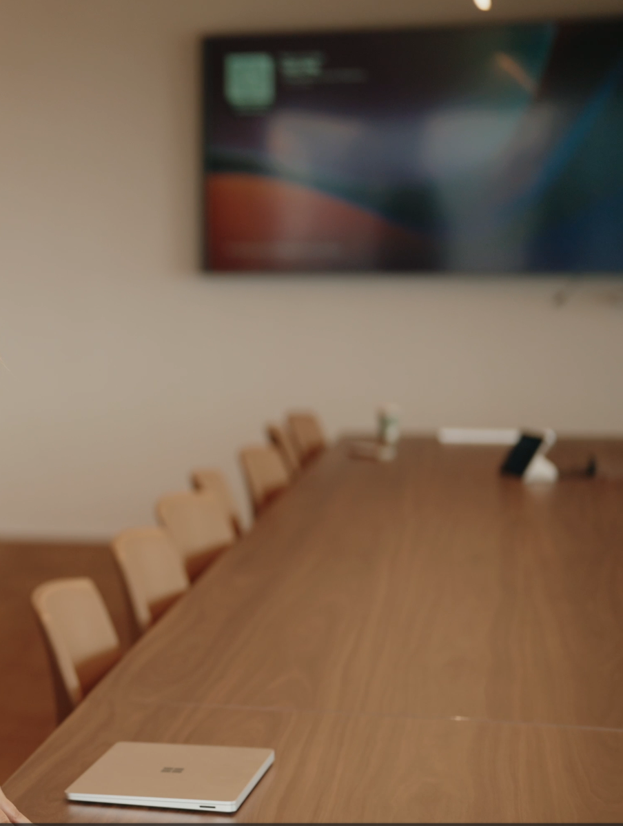 Long boardroom table with a laptop and wall-mounted presentation screen