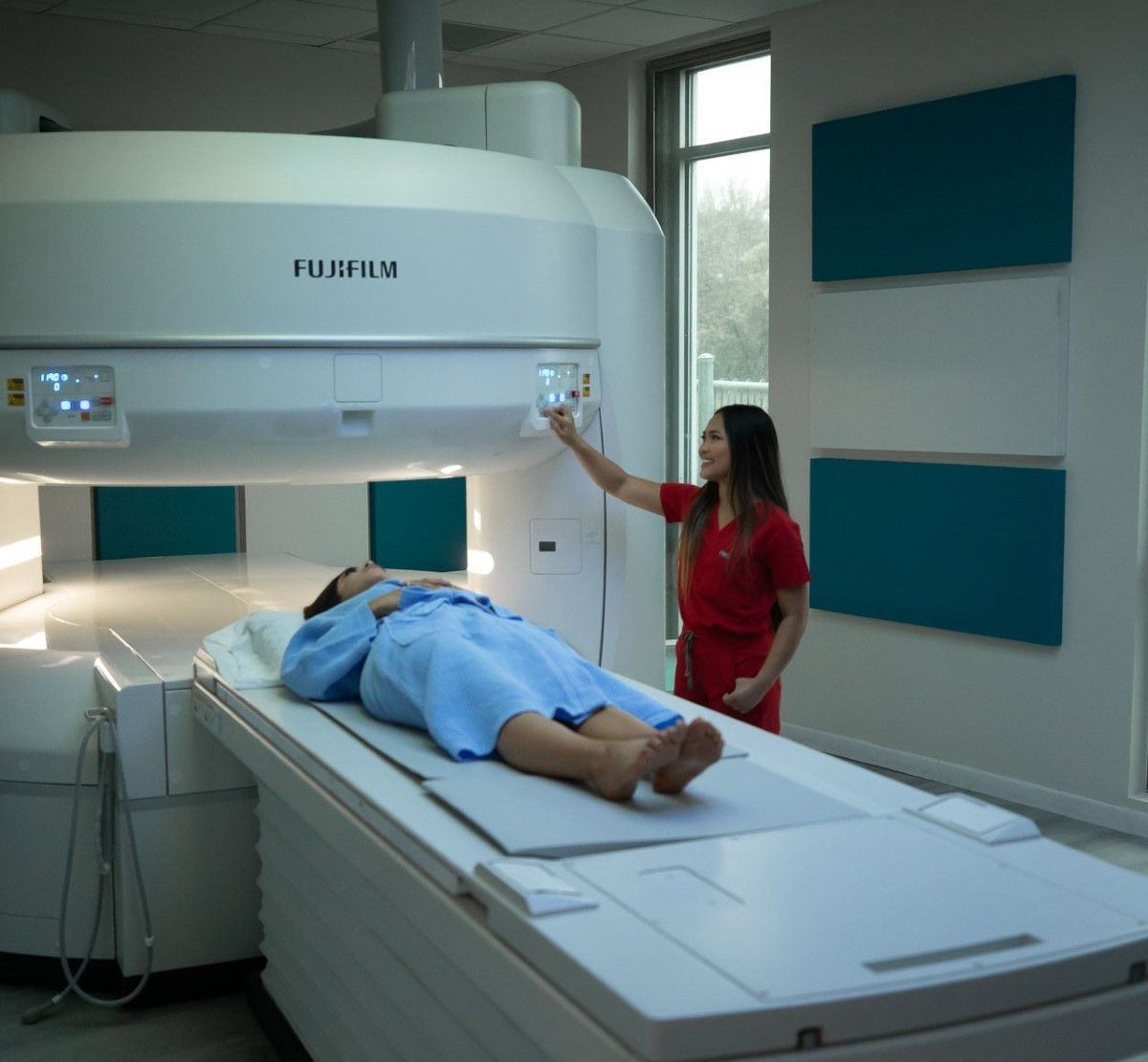 Patient lying on a scan table about to undergo MRI with a technician operating the machine.