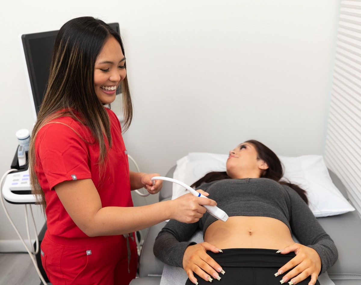 Medical professional performing an ultrasound on a patient's abdomen in a clinical setting.