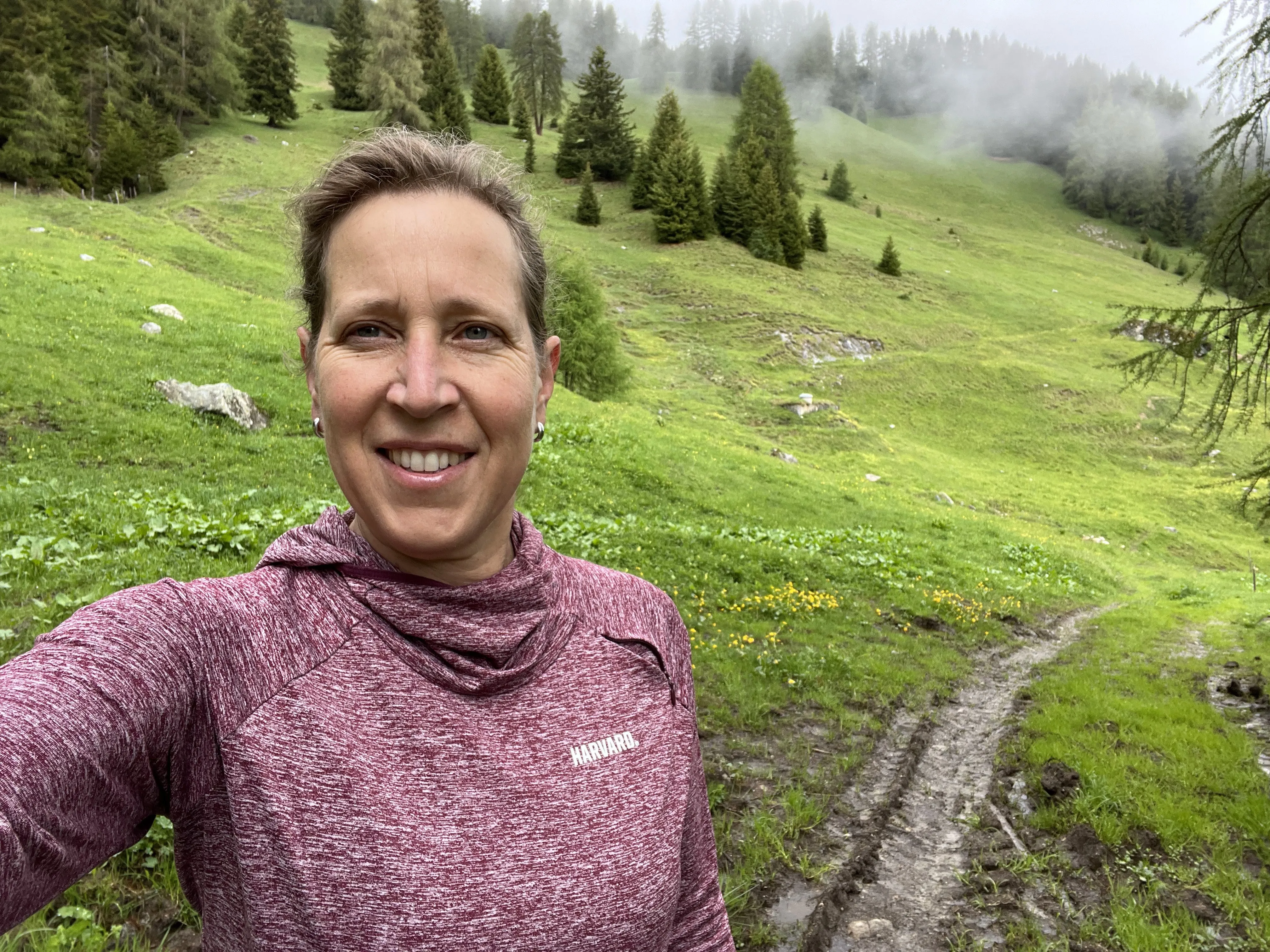 A woman taking a selfie in green pasture while on a hike