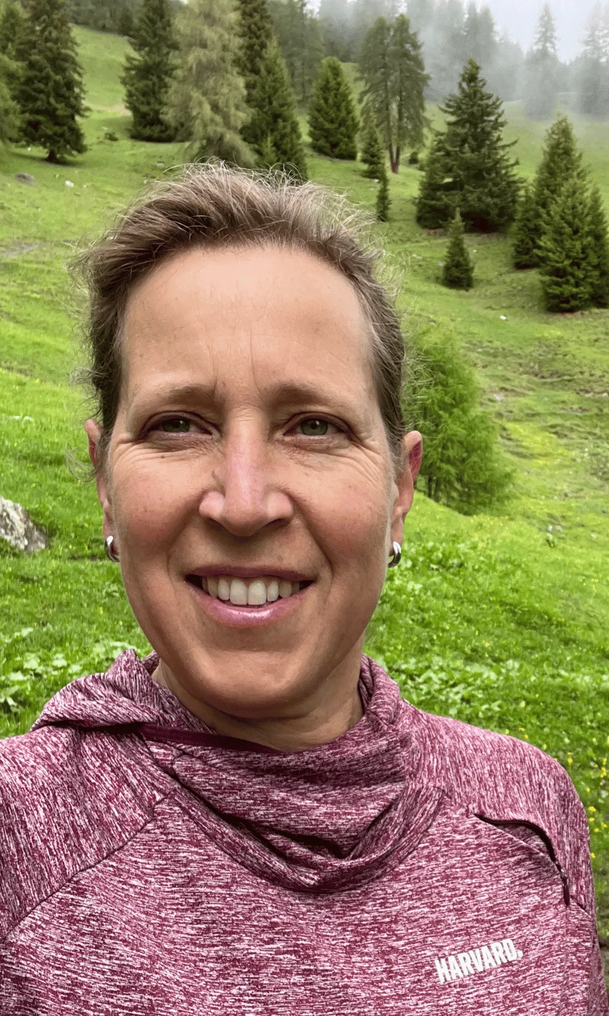 A woman taking a selfie in green pasture while on a hike