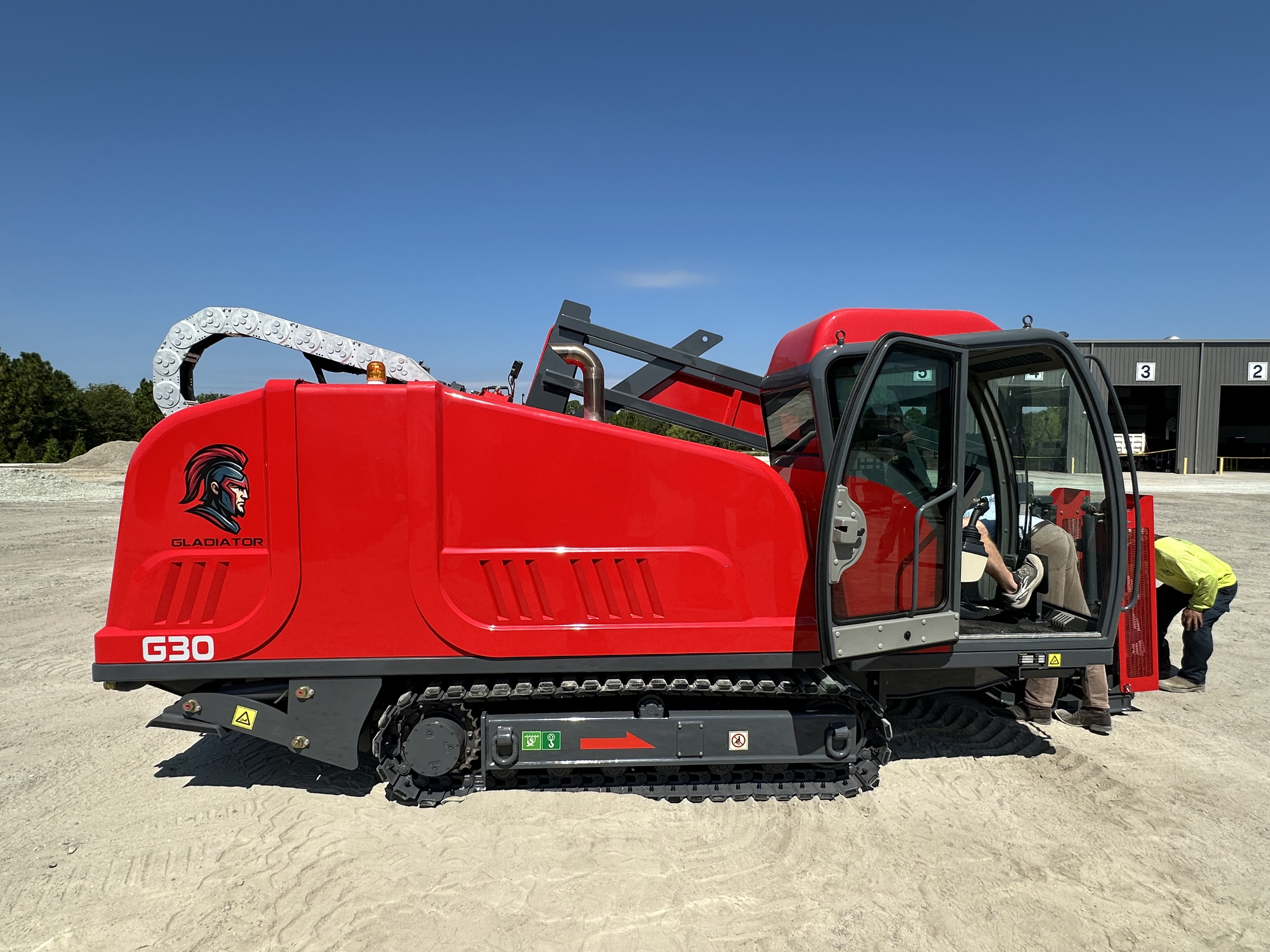 Horizontal directional drill with cab rotated under clear blue sky with person in safety vest nearby.