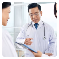 Male doctor wearing a white coat and stethoscope discussing with two colleagues holding a tablet.