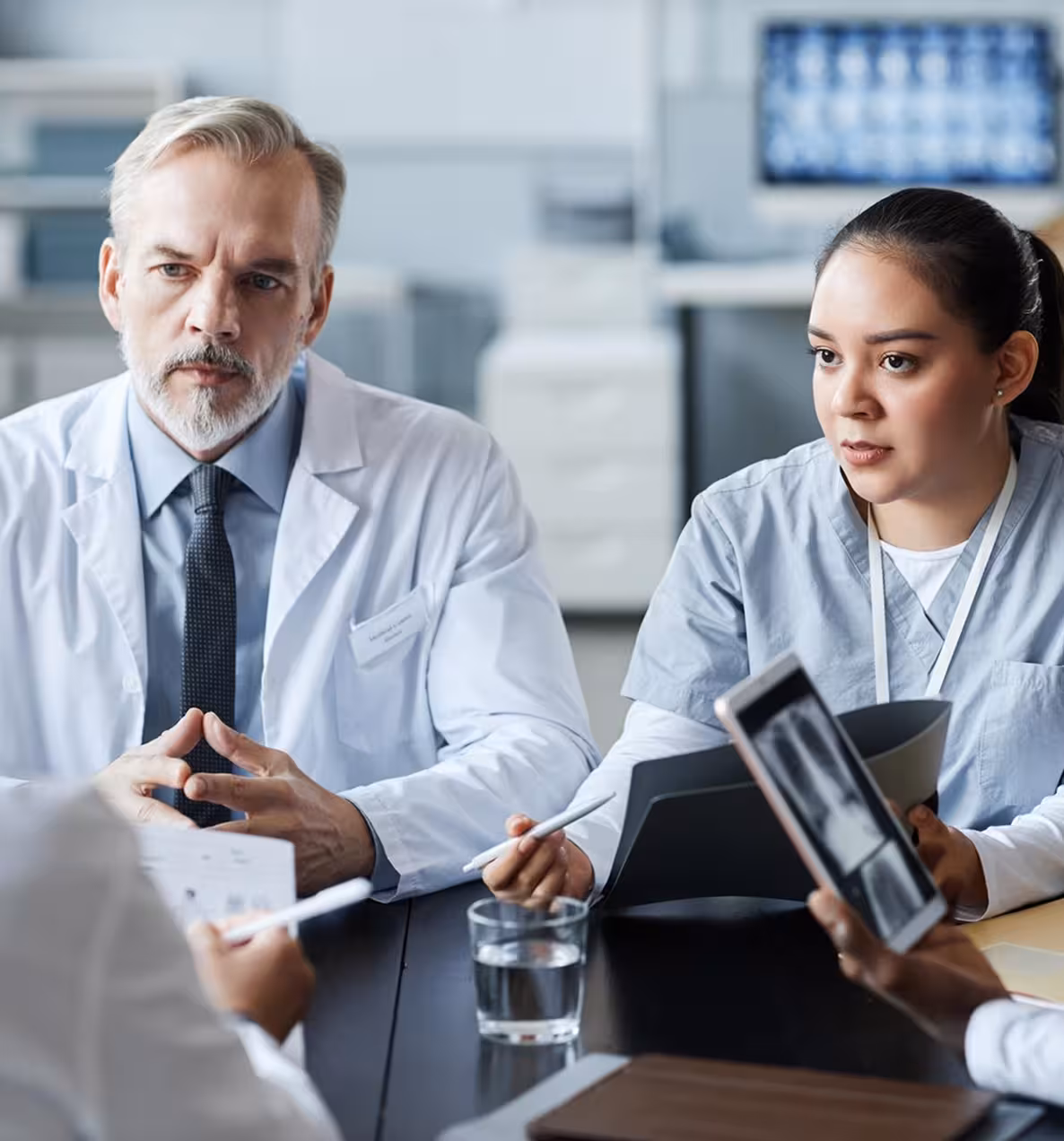 Doctors in a meeting discussing X-ray images and medical documents at a table.