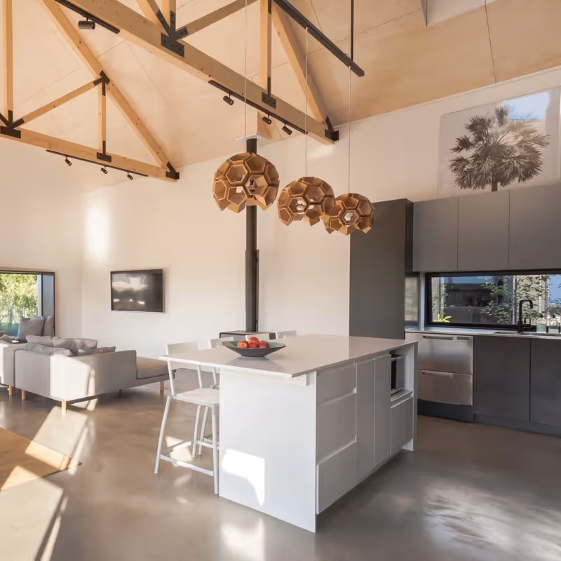 Saunders Residence open-plan living and dining area with grey sofas, dining table, and kitchen island.