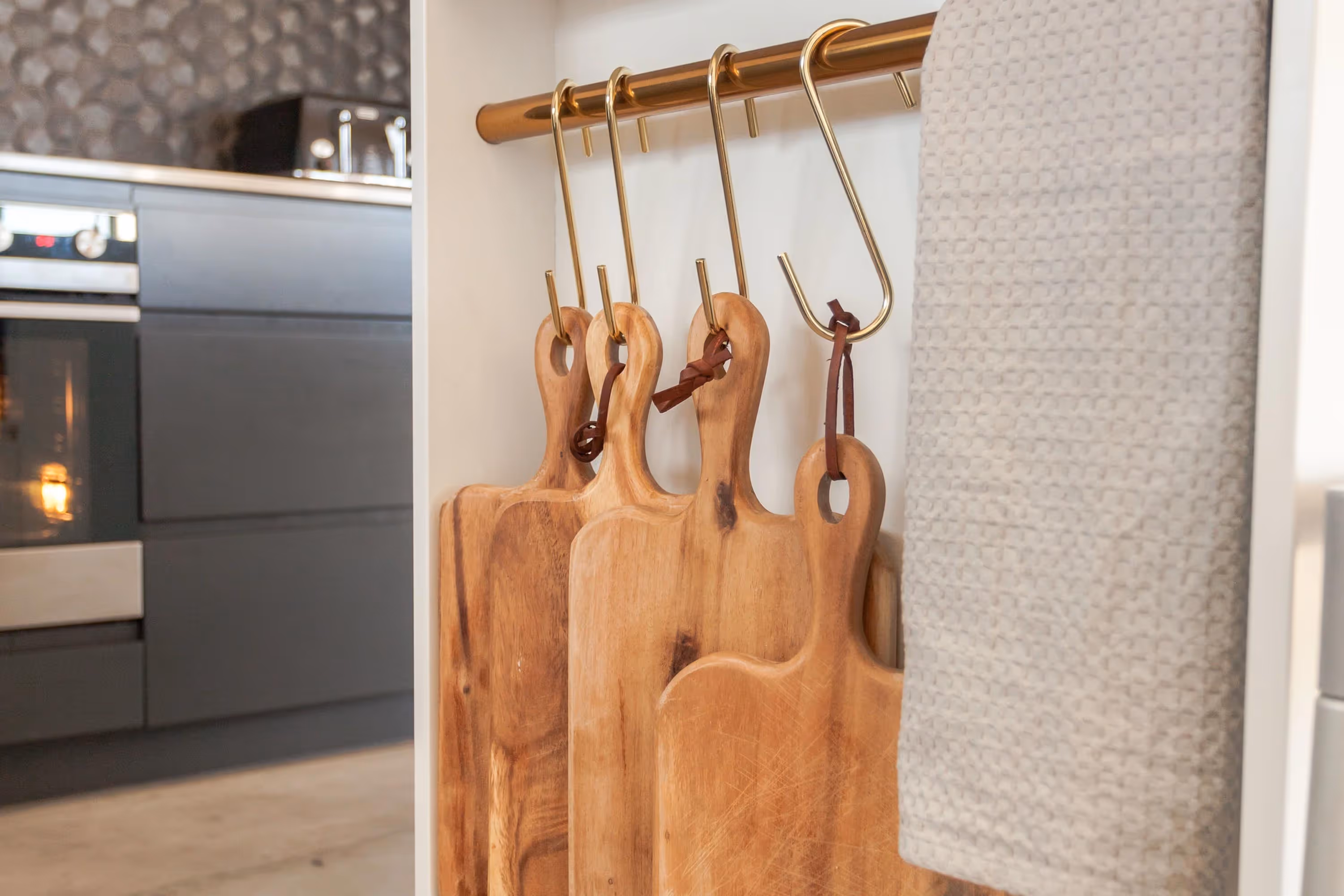 Saunders Residence kitchen detail with wooden cutting boards on gold hooks.