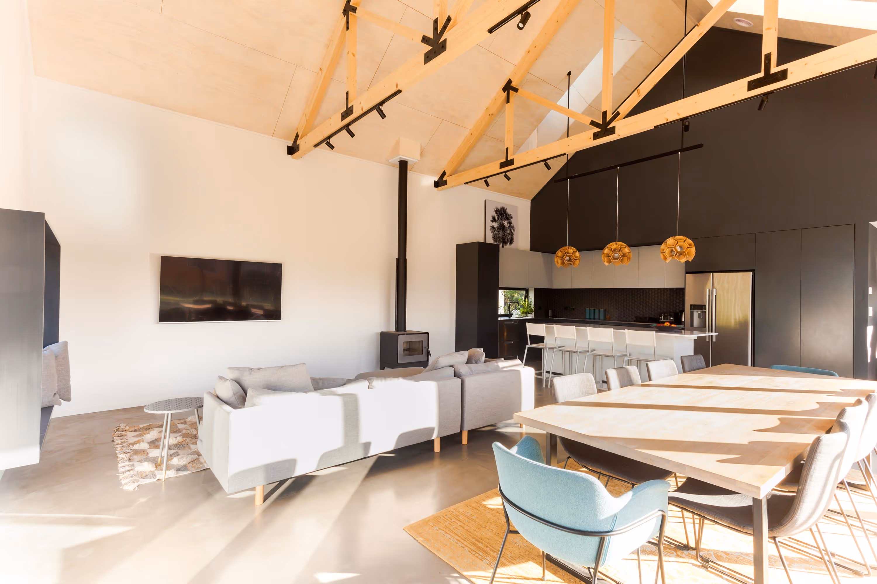 Saunders Residence open-plan living and dining area with grey sofas, dining table, and kitchen island.
