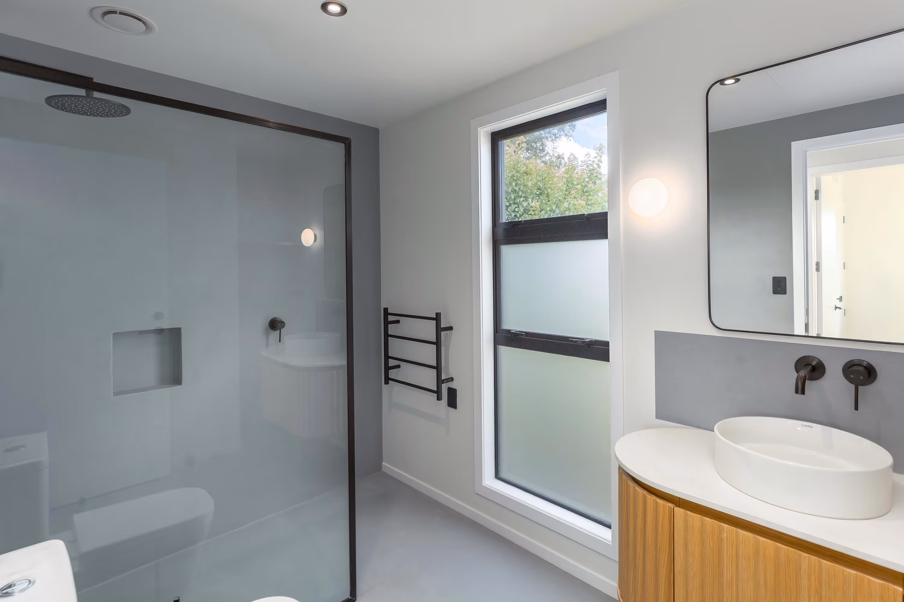 Fisher & Clarke house, bathroom with glass shower, timber vanity, oval sink, and matte black fittings.