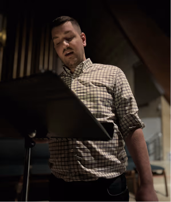 Matt Bridge stands and sings while looking at a music stand