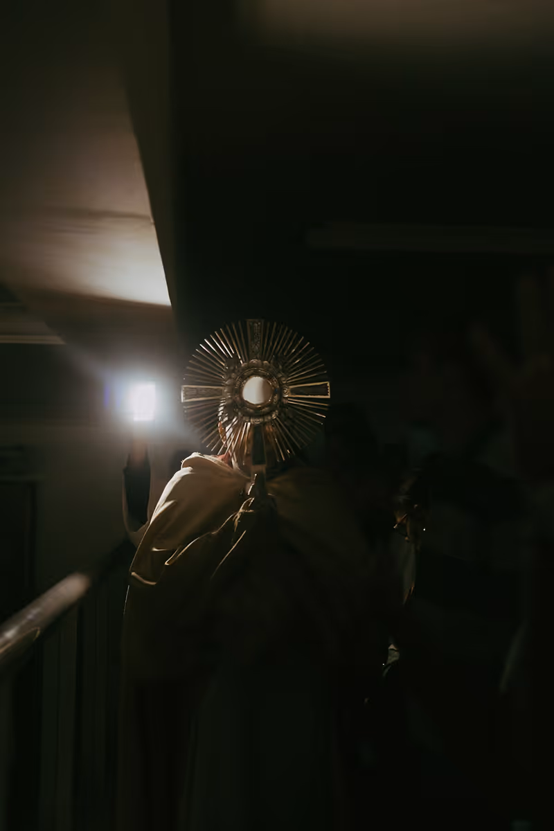 A priest raises up a monstrance containing the Blessed Sacrament