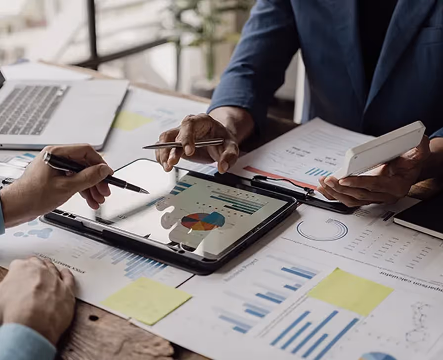 Business team analyzing data charts and graphs on tablet and documents