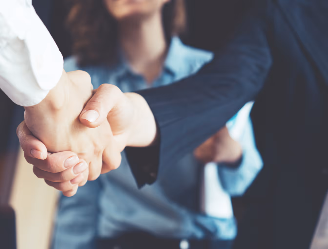 Business professionals in formal attire shaking hands in agreement