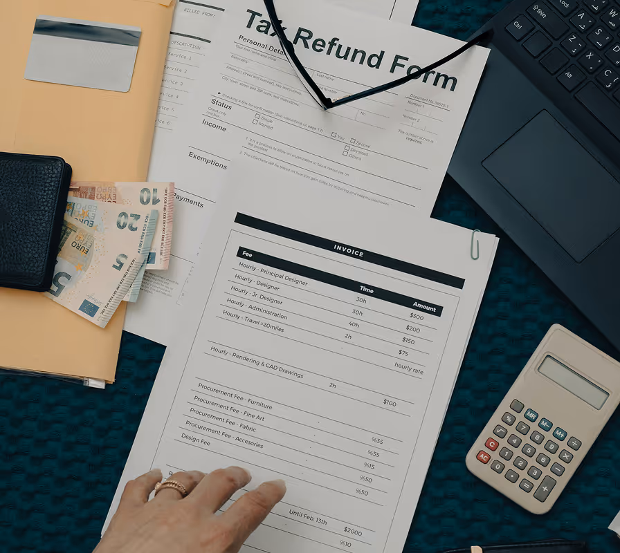 Tax refund form, invoice, cash, calculator, keyboard, and glasses on teal desk.