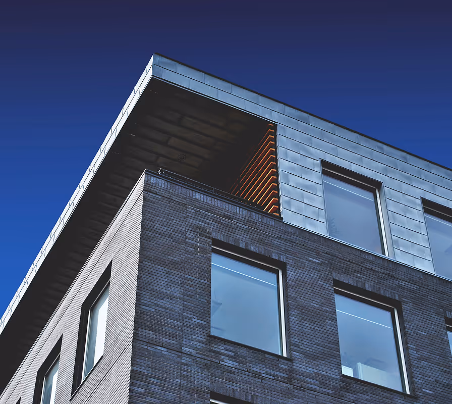 Modern brick building corner with blue sky and reflective windows