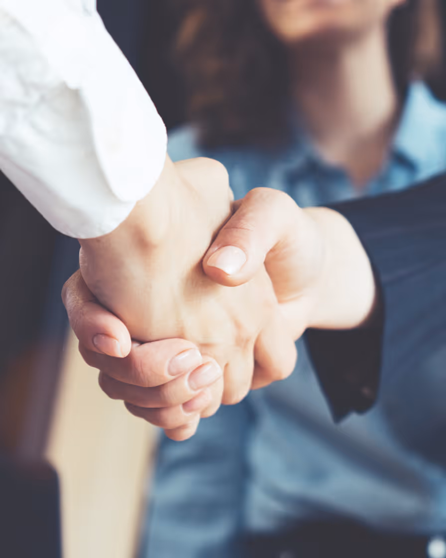Adult's hand gently holding infant's tiny hand in warm sunlight embrace.