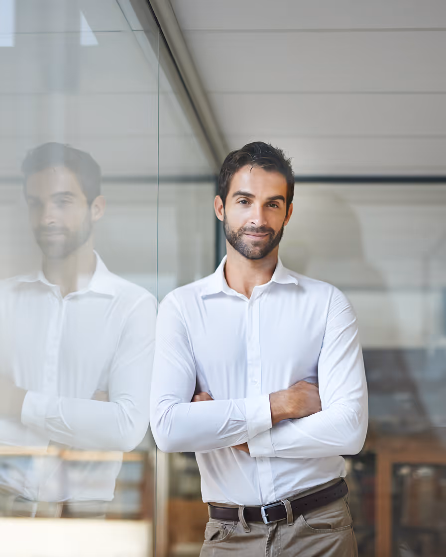Professional man in white shirt standing with arms crossed by glass wall