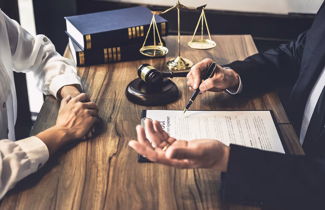 Two lawyers discussing contract with gavel and law books on wooden desk