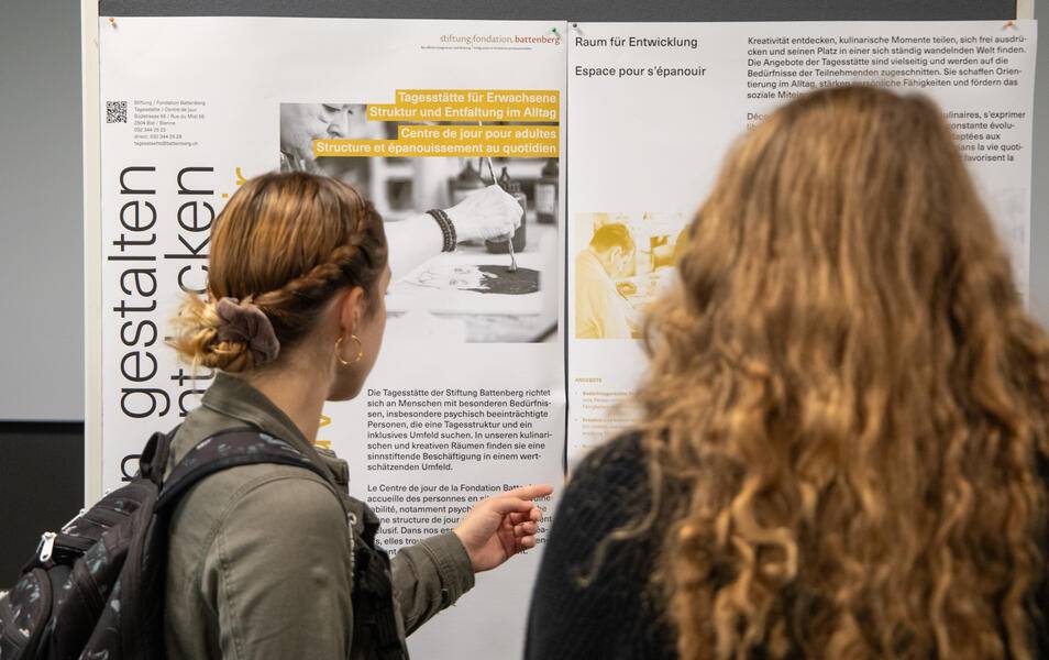 Foto von 15 Personen, die jeweils ein Diplom vor einem weißen Zelt im Freien halten.