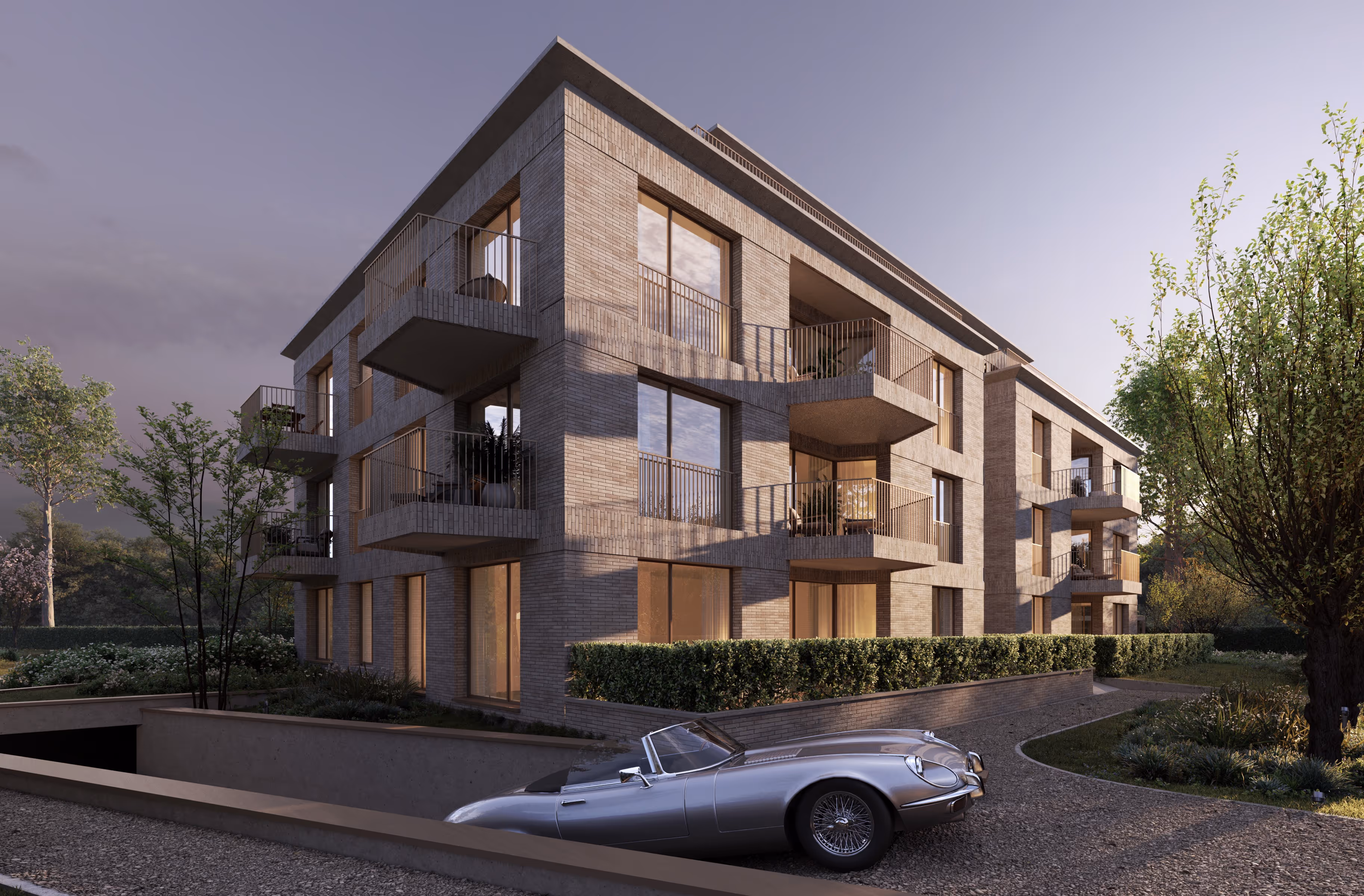 Silver vintage convertible car parked in front of a modern three-story brick apartment building with balconies in a landscaped setting in Wilrijk.