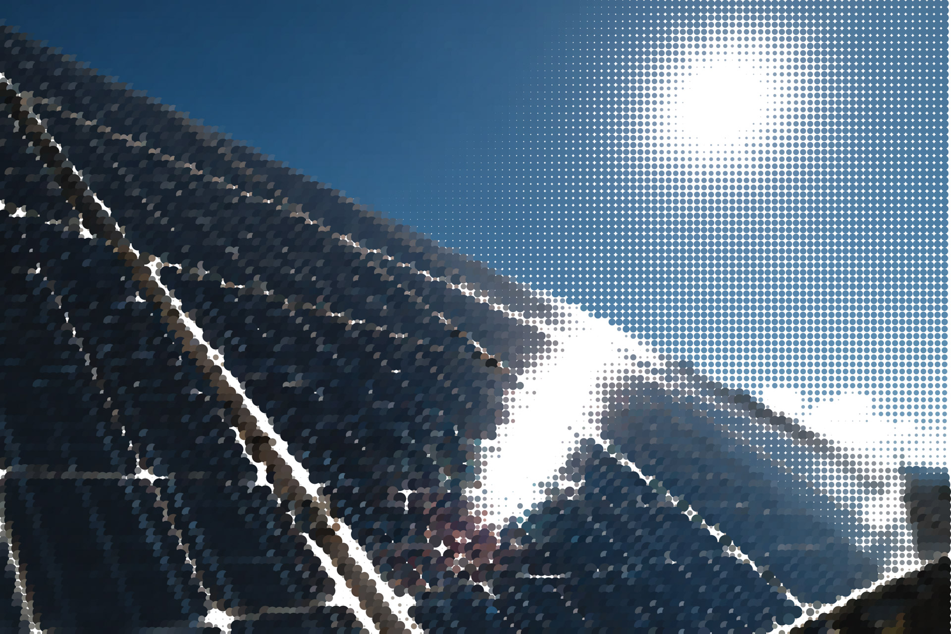 Solar panels angled under a clear blue sky with the bright sun shining above.