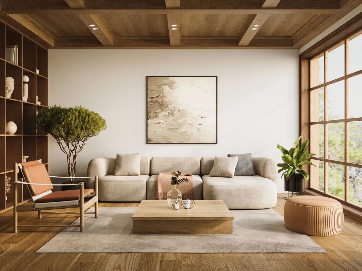 Modern living room with beige sectional sofa, wooden coffee table, orange cushioned chair, large windows, and indoor plants.