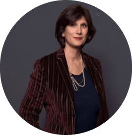 Portrait d'une femme portant un blazer rayé marron et un collier argenté sur fond gris.