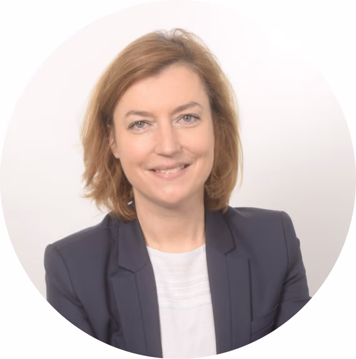 Portrait d'une femme souriante aux cheveux châtains portant un blazer bleu foncé et un chemisier blanc.
