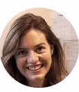 Portrait d'une femme souriante aux cheveux longs et châtains, sur fond neutre flou.