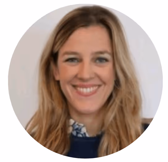 Femme souriante aux cheveux longs blonds, portant un pull bleu et une chemise à col.