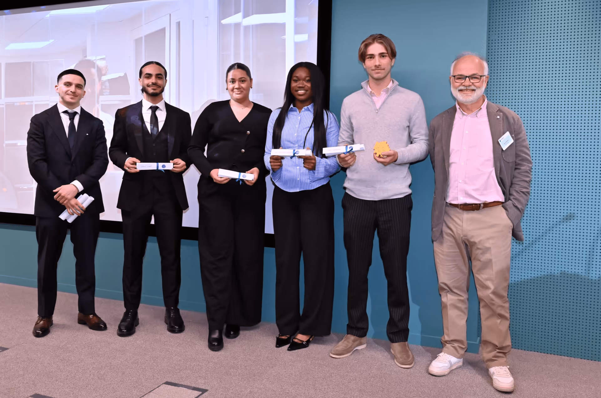 Groupe de six personnes debout, cinq jeunes tiennent des certificats ou trophées lors d'une cérémonie.
