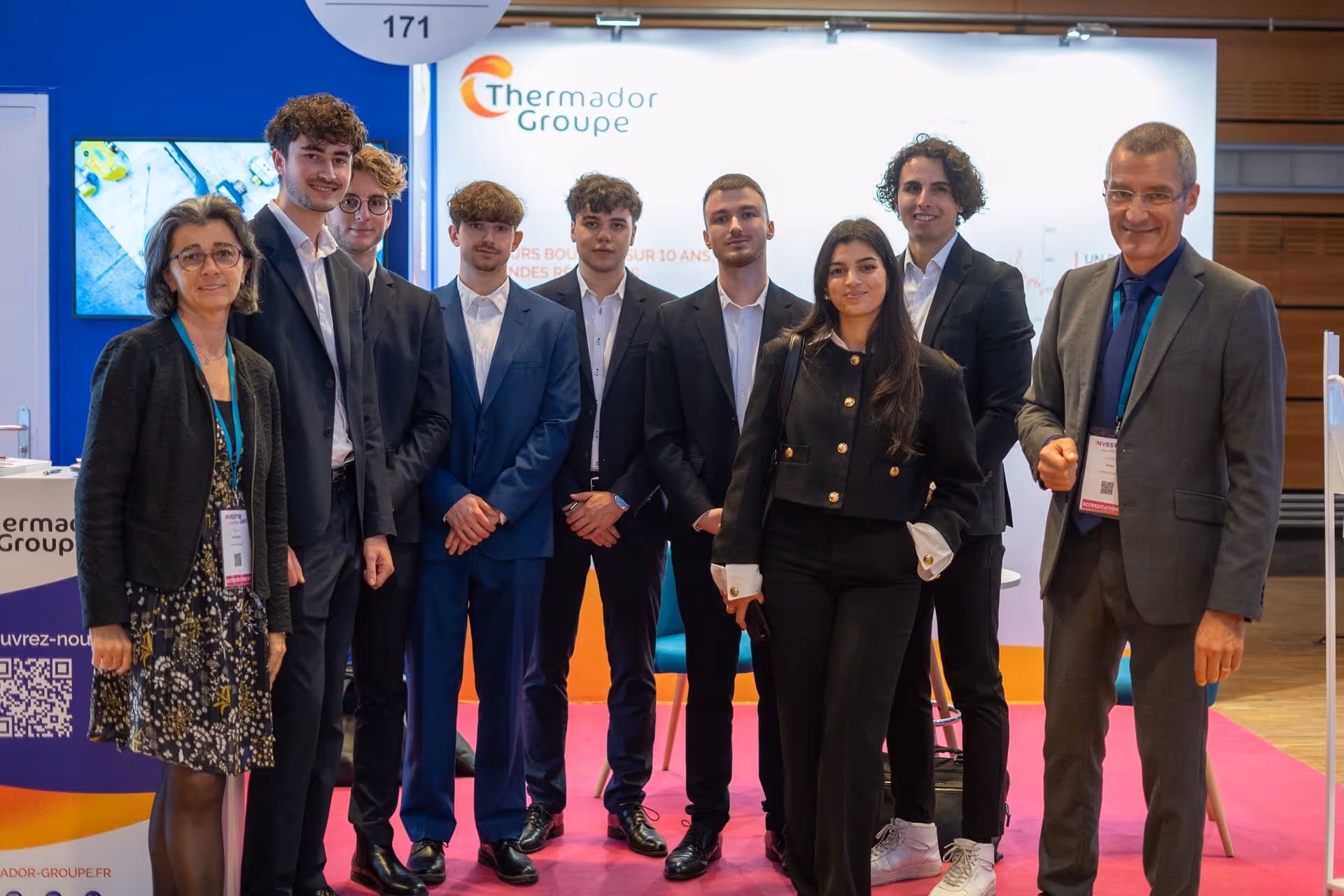 Groupe de huit personnes habillées professionnellement posant devant un stand Thermador Groupe.