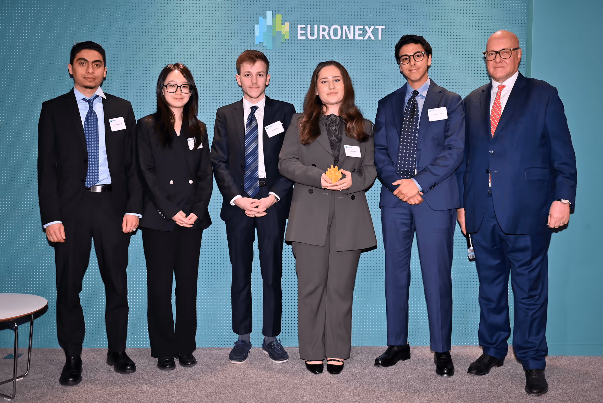 Six personnes en tenue professionnelle posant devant un mur avec le logo Euronext.