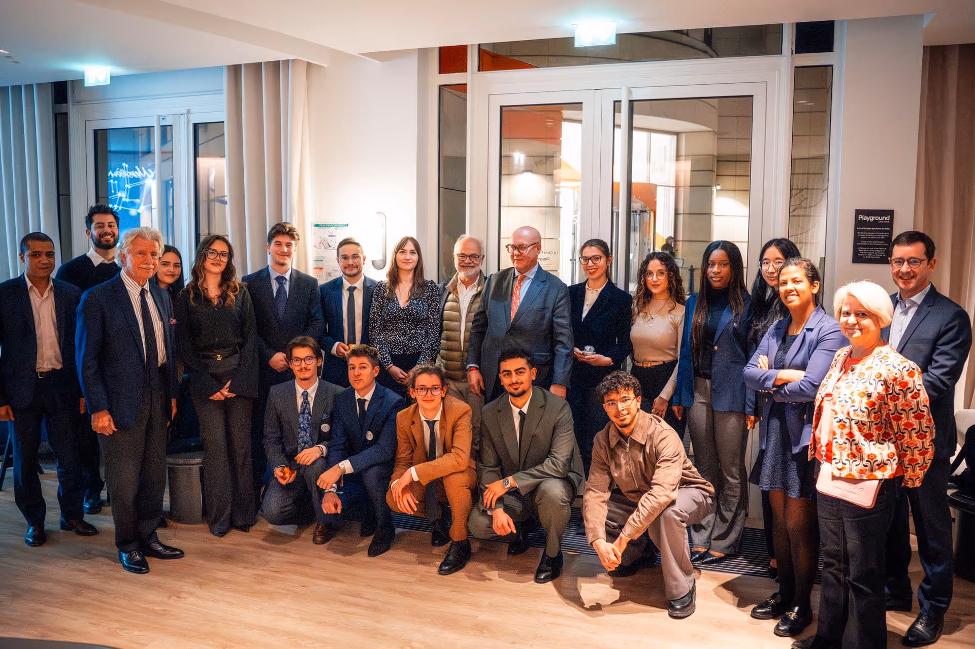 Groupe de personnes souriantes en tenue professionnelle posant dans un intérieur moderne.