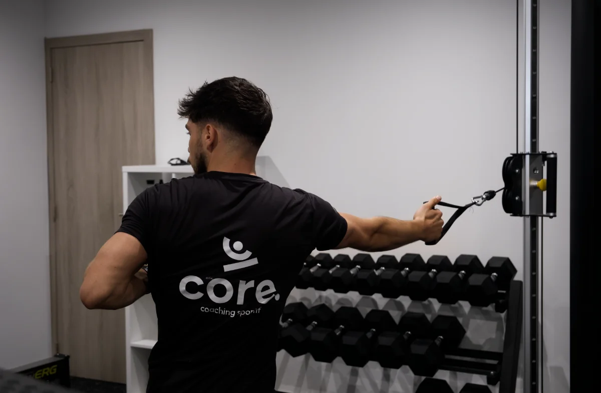 coach sportif en exercice sur poulie dans sa salle de sport