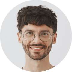 A man with glasses and a beard smiling.