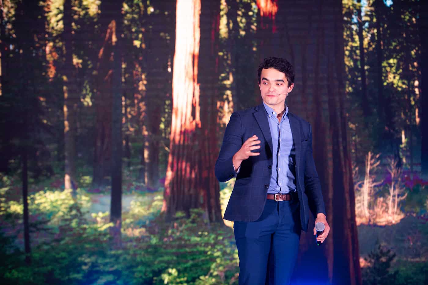 Isma Zmerli on stage, microphone in hand, during a mentalism show
